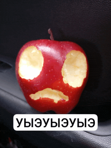 a red apple with a face carved into it sits on a car door