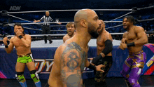 a group of wrestlers are standing in a ring with the aew logo on the bottom left