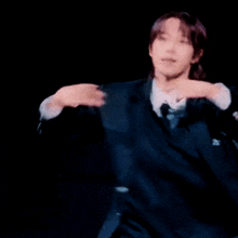 a man in a black suit is making a funny face with his hand