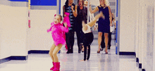 a girl in a pink outfit is doing a handstand in a hallway with other women