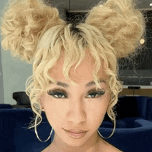 a woman with blonde curly hair has two buns on her head