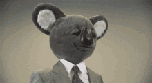 a stuffed koala wearing a suit and tie winks at the camera