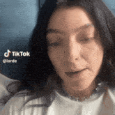 a close up of a woman 's face with the words tiktok @lorde below her