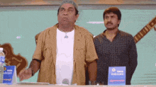 two men are standing in front of a table with a sign that says tata