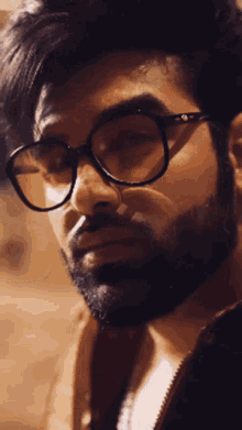 a man with glasses and a beard is looking down