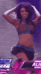 a woman is dancing in front of a screen that says alicia wwe