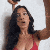 a woman in a red bikini is taking a selfie with her mouth open .