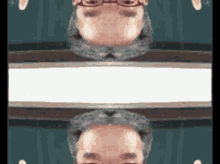 a man 's face is reflected in a mirror while wearing glasses
