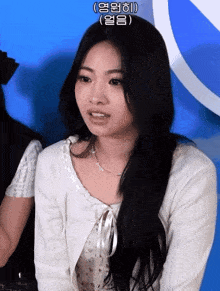 a girl with long black hair is wearing a white top and a white cardigan