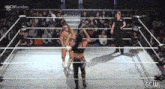a woman is standing in a wrestling ring with a referee .