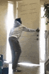 a man in a hoodie is standing in front of a door