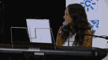 a woman singing into a korg microphone while playing a keyboard