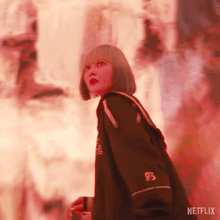 a woman in a black jacket and red lipstick is standing in front of a red background .