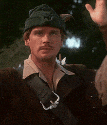 a man wearing a green hat with a s on it holds his head