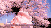 a woman in a pink dress is standing in front of a cherry blossom tree