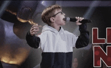 a young boy is singing into a microphone in front of a robot .