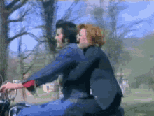 a man and woman are riding a motorcycle in a field