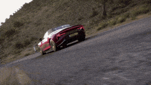 a red sports car with a g on the front is driving down a road