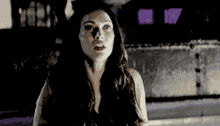 a woman with long hair is standing in front of a building with purple lights behind her .