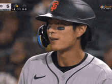 a baseball player wearing a sf hat looks at the scoreboard