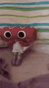 a stuffed animal is sitting on a bed with a striped blanket behind it