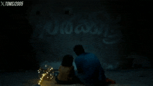 a man and a child are sitting in front of a wall that says ' toms 2005 ' on it