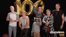 a group of men are standing in front of balloons with the number 100 on them
