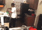 a man in a white shirt is standing in a kitchen cooking