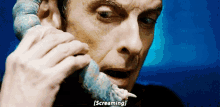 a man is screaming while holding a blue object in his mouth