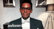 a man in a suit and bow tie is making a funny face while wearing glasses .