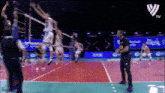 a group of volleyball players are playing on a court with a man in a black shirt standing in front of them