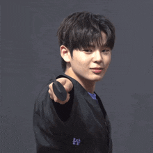 a young man in a black jacket is pointing his finger
