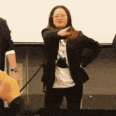 a woman in a black jacket and glasses is dancing