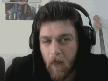 a man with a beard wearing headphones and a hat .