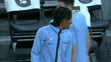 a basketball player wearing a light blue nike jacket