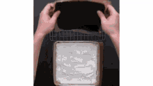 a person is putting a piece of chocolate cake on top of a pan of whipped cream .