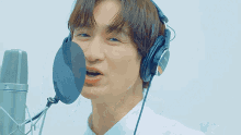 a man wearing a pair of sony headphones stands in front of a microphone