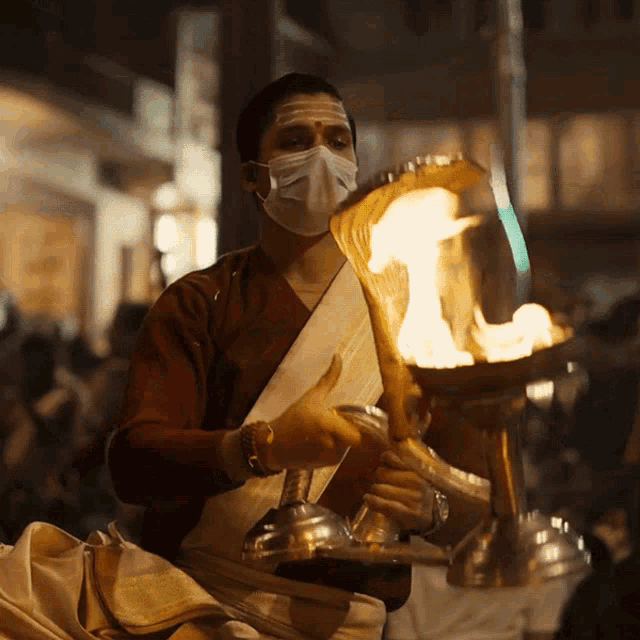 a man wearing a face mask is holding a torch in his hands