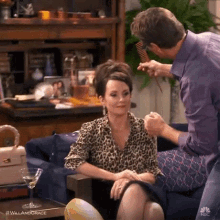 a man is combling a woman 's hair while she sits on a couch .