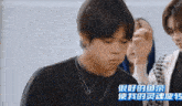 a young man wearing a black shirt and a necklace with chinese writing on the bottom