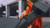 a person in an orange jacket is holding a black object
