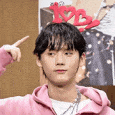 a young man wearing a pink hoodie has a headband with hearts and the word love on it