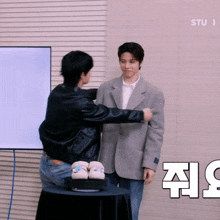 two men are standing next to each other in front of a white board that says studio