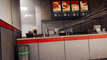 a man stands at a counter in a fast food restaurant with a menu behind him