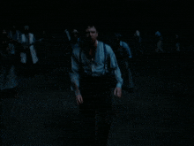 a man in suspenders is walking in the dark