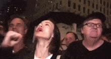 a group of people are standing in a crowd and looking up at something .