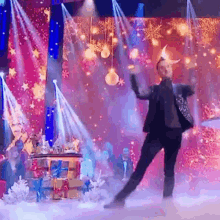 a man in a suit is dancing on a stage in front of a christmas tree .