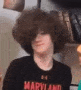a young man with a large afro is wearing a maryland shirt .