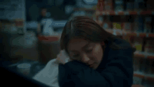 a woman in a black jacket is sitting in a dark room .