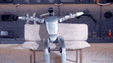 a robot is sitting on a couch with a gifrun.com logo in the corner